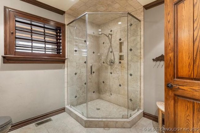 bathroom with crown molding, toilet, and a shower with shower door