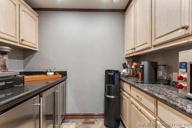 kitchen with crown molding, light brown cabinets, and dark stone counters