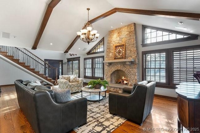 living room featuring hardwood / wood-style floors, beam ceiling, high vaulted ceiling, a stone fireplace, and a chandelier