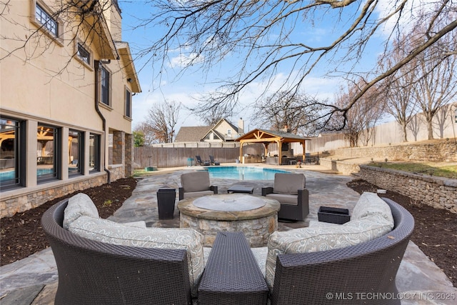 view of patio / terrace featuring a gazebo, a fenced in pool, and an outdoor living space with a fire pit