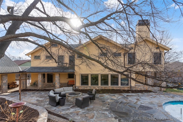 rear view of property featuring a patio area and a fire pit