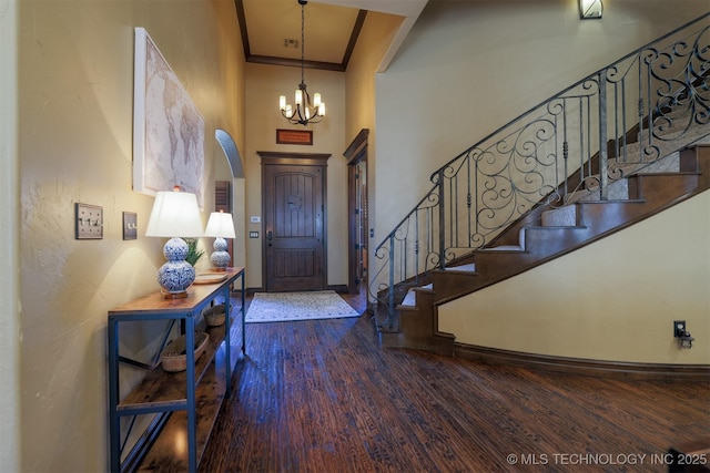 foyer featuring an inviting chandelier, ornamental molding, and dark hardwood / wood-style floors