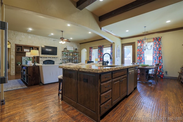 kitchen with an island with sink, sink, stainless steel dishwasher, and dark wood-type flooring