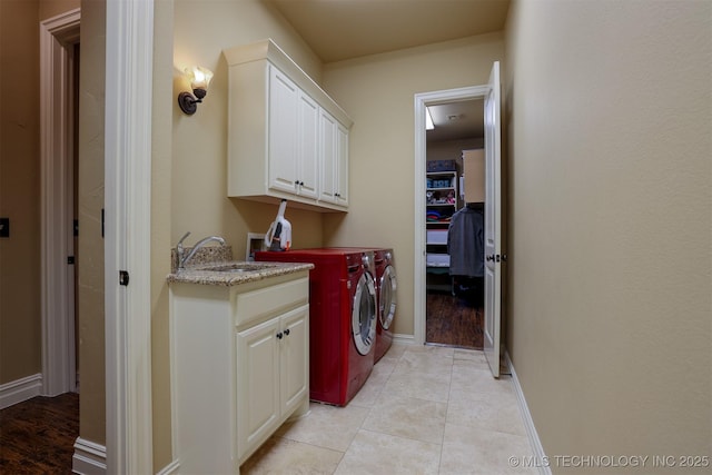 laundry area with cabinets, separate washer and dryer, sink, and light tile patterned floors