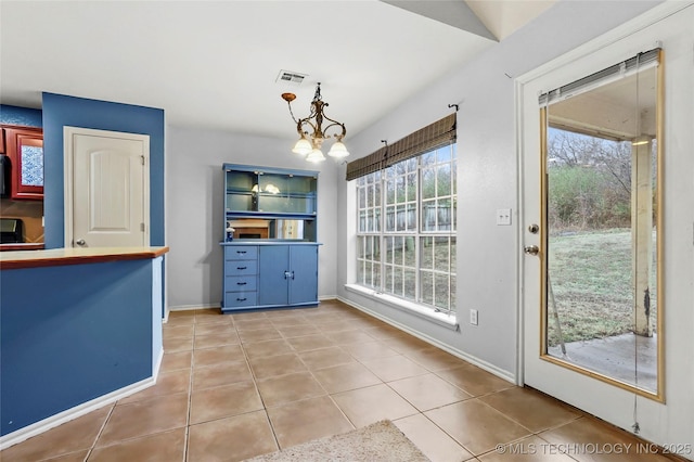 unfurnished dining area featuring light tile patterned flooring and a chandelier