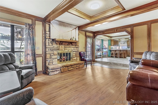 living room with coffered ceiling, beam ceiling, crown molding, hardwood / wood-style flooring, and a fireplace