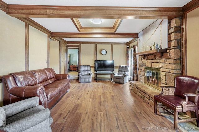 living room featuring beamed ceiling, crown molding, a stone fireplace, and light wood-type flooring