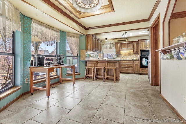 kitchen featuring light tile patterned flooring, a breakfast bar, black microwave, ornamental molding, and kitchen peninsula