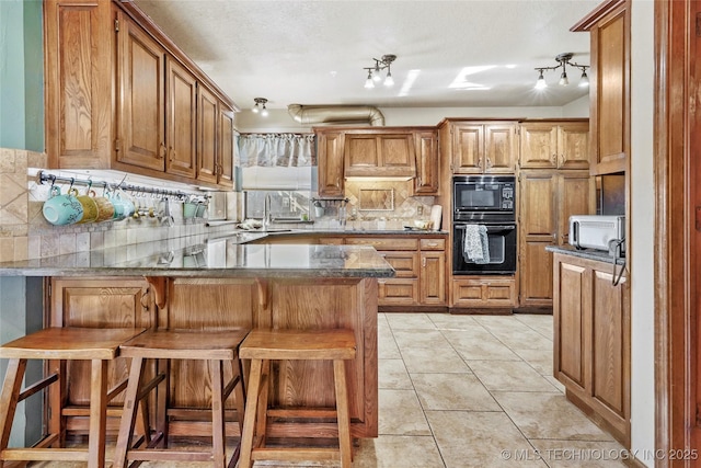 kitchen with tasteful backsplash, black appliances, sink, a kitchen breakfast bar, and kitchen peninsula