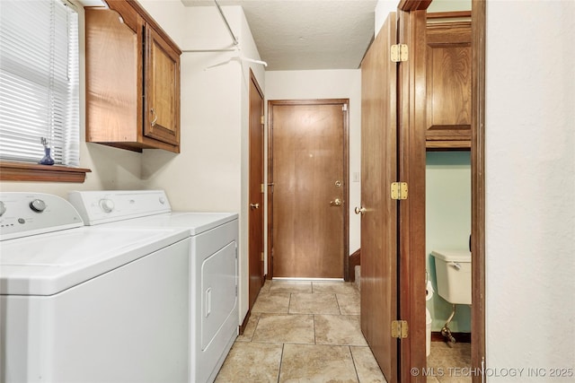 clothes washing area with independent washer and dryer, cabinets, and a textured ceiling