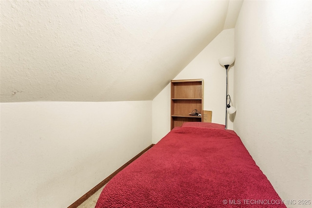 bedroom with vaulted ceiling, carpet, and a textured ceiling