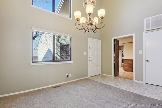 carpeted foyer with a towering ceiling and a chandelier