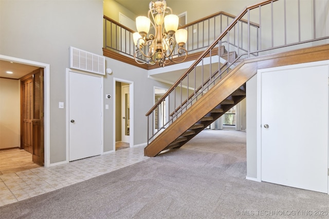 foyer entrance with an inviting chandelier, light colored carpet, and a high ceiling