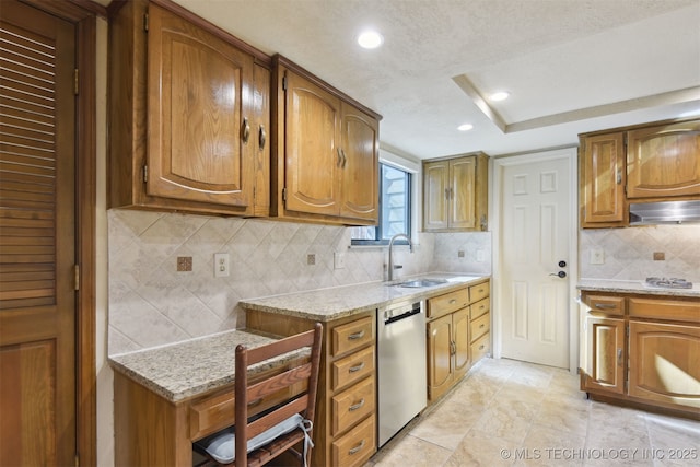 kitchen featuring light stone counters, stainless steel dishwasher, sink, and backsplash