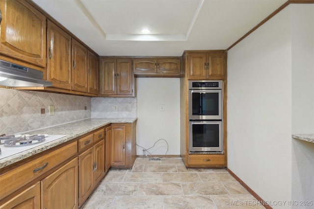 kitchen featuring tasteful backsplash, white gas cooktop, a raised ceiling, stainless steel double oven, and light stone countertops