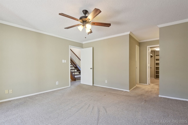 carpeted spare room with ceiling fan, ornamental molding, and a textured ceiling