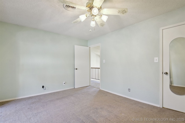 empty room featuring ceiling fan, light colored carpet, and a textured ceiling