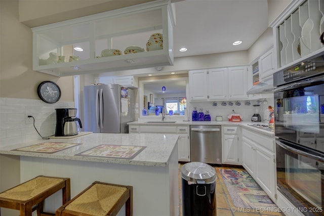 kitchen featuring a peninsula, white cabinetry, stainless steel appliances, and a sink