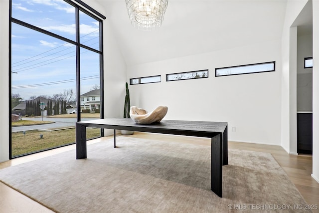 unfurnished office with an inviting chandelier, high vaulted ceiling, plenty of natural light, and hardwood / wood-style floors
