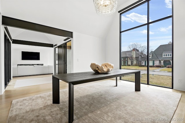 unfurnished office featuring lofted ceiling, a notable chandelier, and light hardwood / wood-style floors