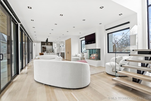 living room featuring a multi sided fireplace and light hardwood / wood-style floors