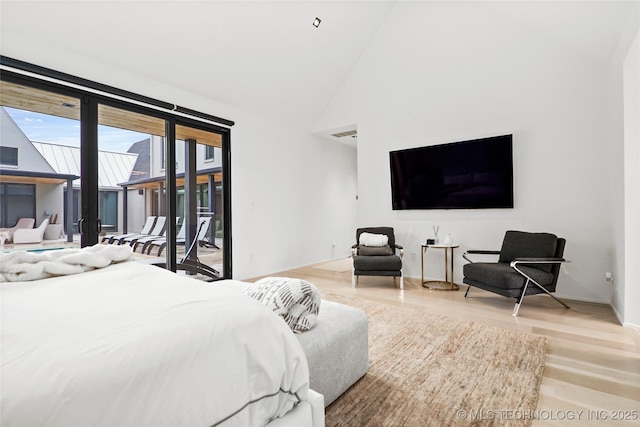 bedroom featuring access to exterior, high vaulted ceiling, and light wood-type flooring