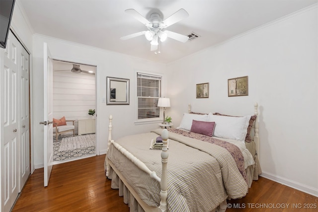 bedroom with crown molding, dark wood-type flooring, ceiling fan, and a closet