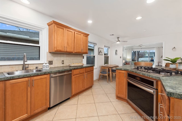 kitchen featuring sink, ceiling fan, appliances with stainless steel finishes, backsplash, and light tile patterned flooring