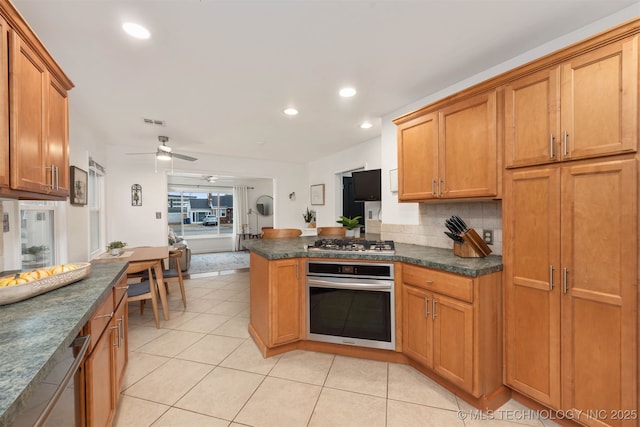 kitchen featuring ceiling fan, stainless steel appliances, tasteful backsplash, light tile patterned flooring, and kitchen peninsula