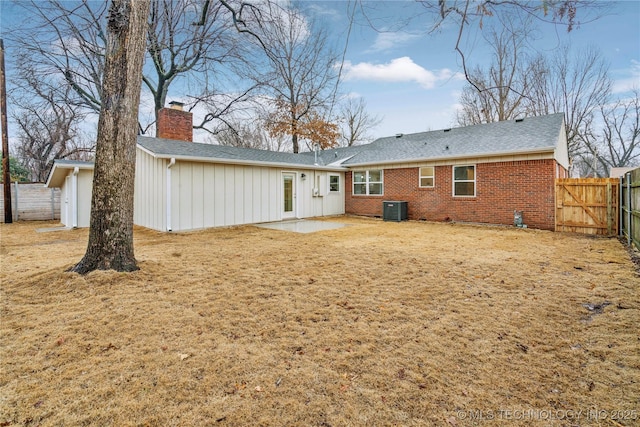 back of property with central AC unit, a patio area, and a lawn