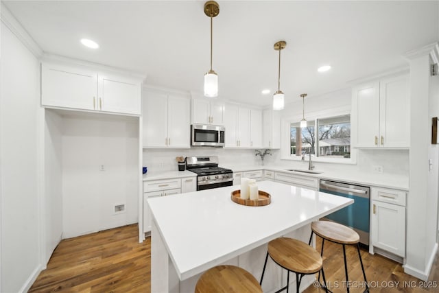 kitchen with pendant lighting, stainless steel appliances, a center island, and white cabinets