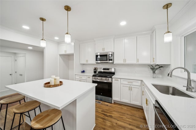 kitchen featuring appliances with stainless steel finishes, sink, white cabinets, and decorative light fixtures