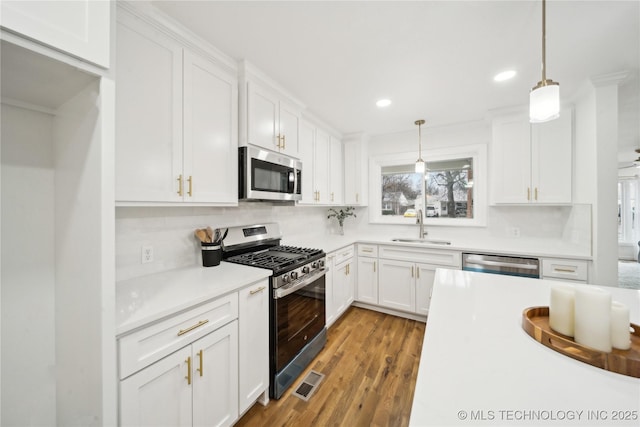 kitchen with white cabinetry, hanging light fixtures, and stainless steel appliances