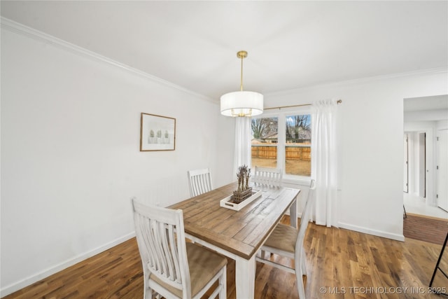 dining space with hardwood / wood-style flooring, crown molding, and a notable chandelier