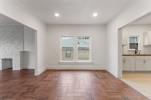 interior space featuring crown molding, dark parquet flooring, a stone fireplace, and sink