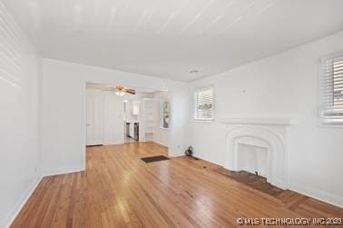 unfurnished living room featuring a wealth of natural light, hardwood / wood-style floors, and ceiling fan