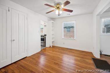 unfurnished bedroom with multiple windows, wood-type flooring, and ceiling fan