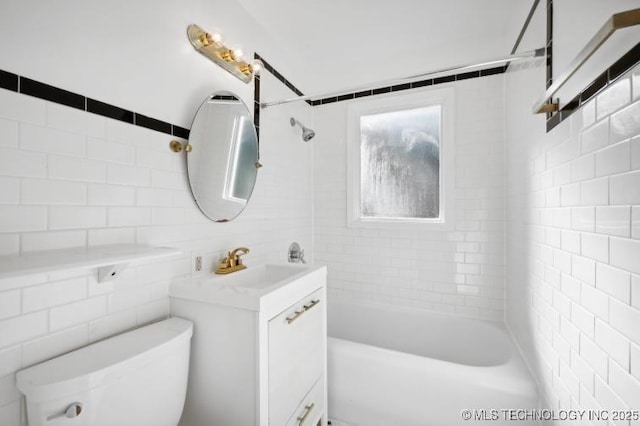 full bathroom with vanity, tiled shower / bath, tile walls, and toilet