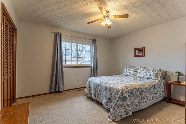 bedroom with ceiling fan, light colored carpet, a closet, and a textured ceiling