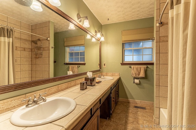 bathroom with vanity, tile patterned floors, shower / bath combination with curtain, and a textured ceiling