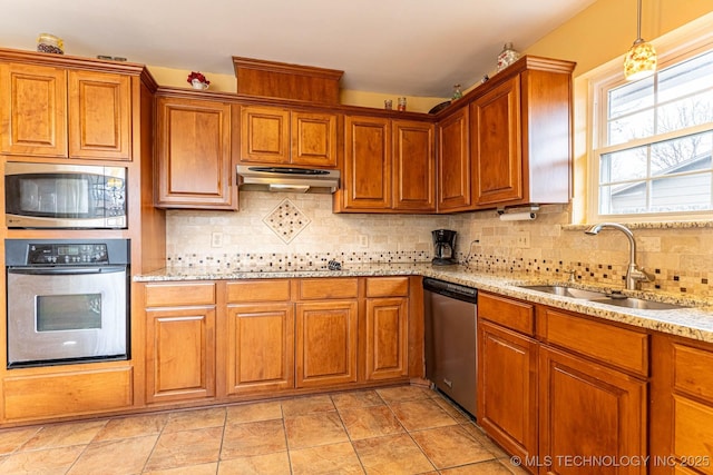 kitchen featuring sink, tasteful backsplash, hanging light fixtures, appliances with stainless steel finishes, and light stone countertops