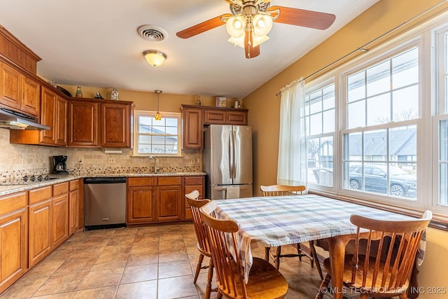 kitchen with appliances with stainless steel finishes, decorative light fixtures, sink, backsplash, and light tile patterned floors