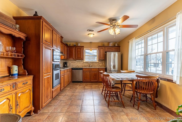 kitchen with sink, light tile patterned floors, ceiling fan, stainless steel appliances, and decorative backsplash