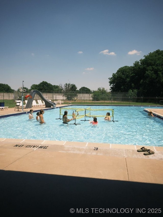 view of pool with a water slide and a patio area