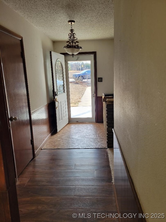 entryway with dark hardwood / wood-style flooring, a chandelier, and a textured ceiling