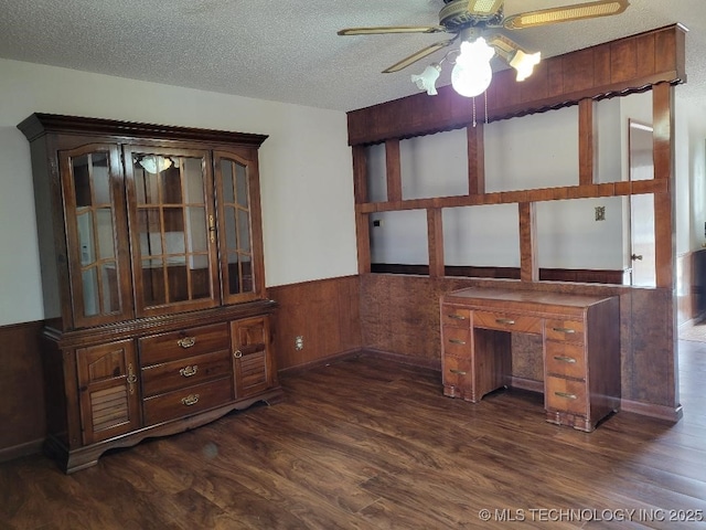 unfurnished office with wooden walls, ceiling fan, dark hardwood / wood-style floors, and a textured ceiling