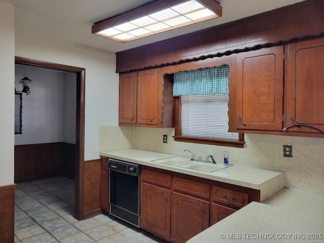 kitchen with sink, black dishwasher, and wood walls