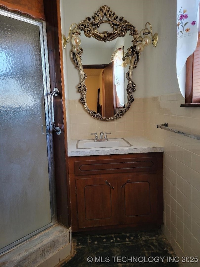 bathroom with vanity, an enclosed shower, and tile walls