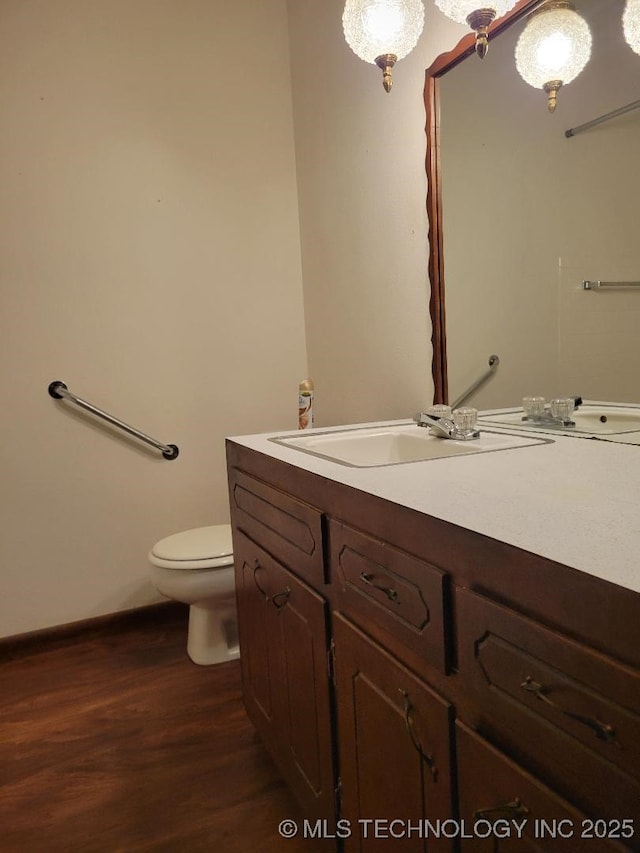 bathroom with wood-type flooring, vanity, and toilet