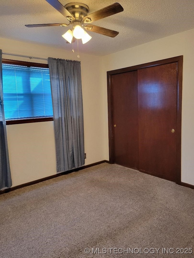 unfurnished bedroom featuring ceiling fan, carpet floors, a closet, and a textured ceiling